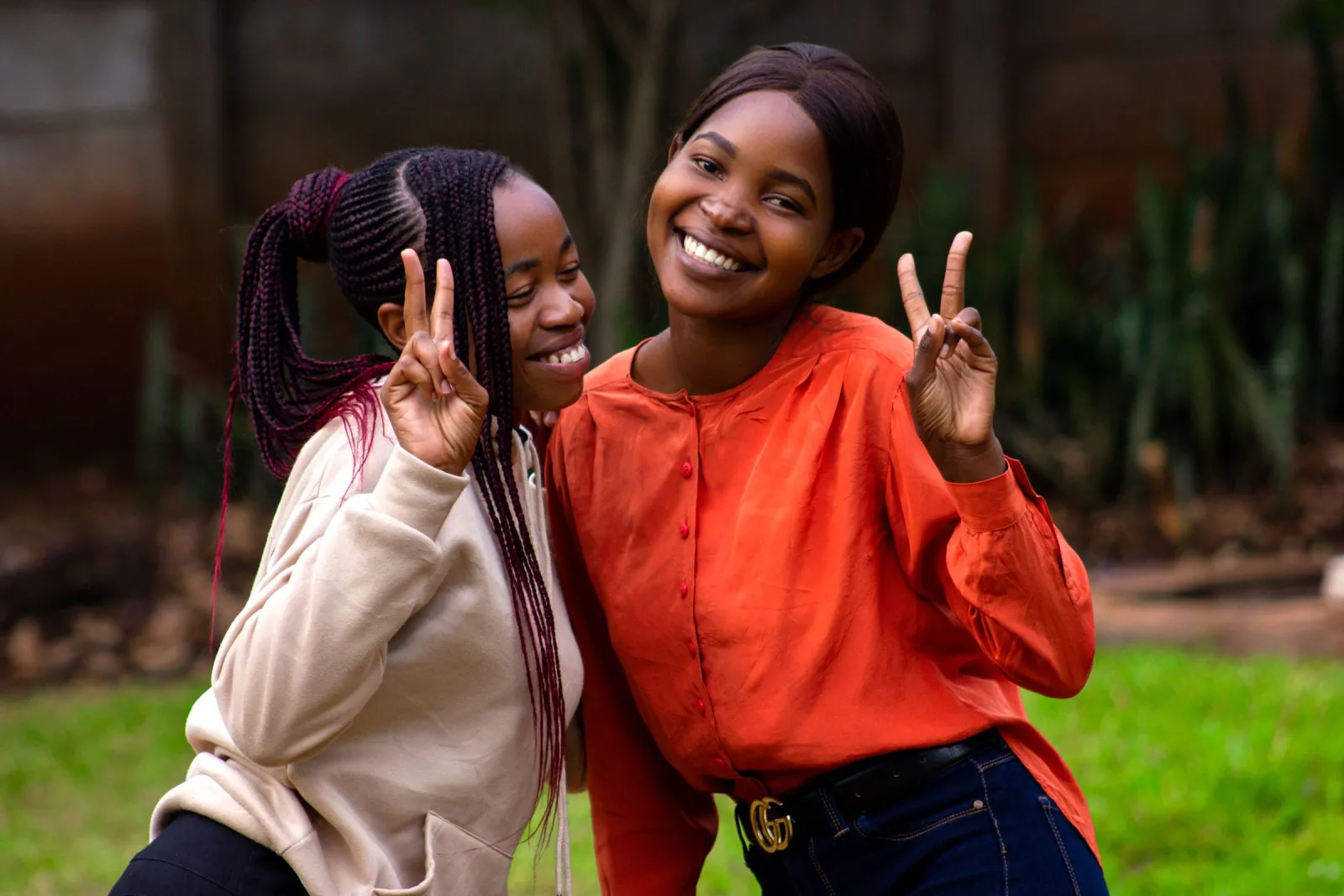 Two young women smiling, one making a peace sign